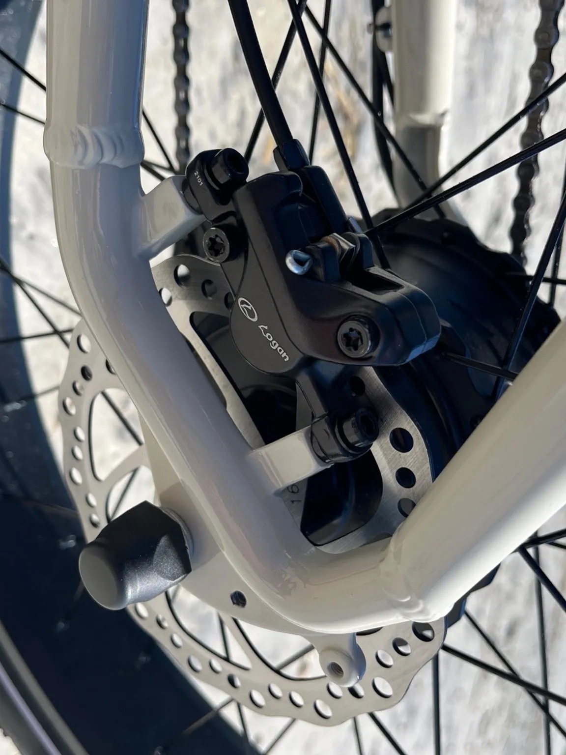 Close-up of a hydraulic disc brake caliper and rotor on a cream e-bike